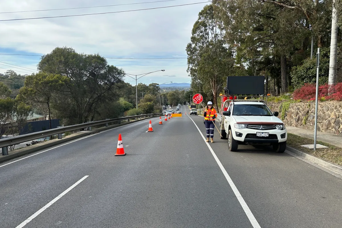 BTM traffic management controller with stop sign and cones ensuring safe roadwork operations in Victoria