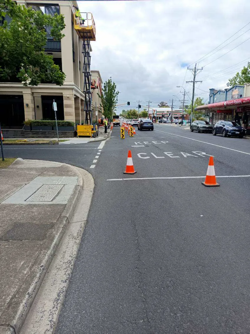 Traffic management setup with cones and signage on a suburban street ensuring safety during building works